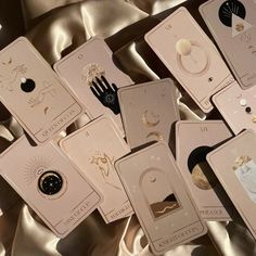 several cards with different designs on them laying on a satin material background, one has a black hand and the other is gold