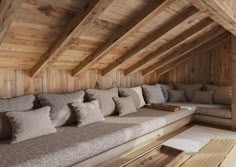 a room filled with lots of couches covered in pillows next to a wooden wall