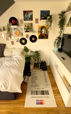 a bed room with a neatly made bed and lots of pictures on the wall above it