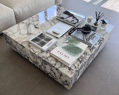 a marble coffee table with books and candles on it