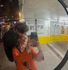 a man and woman taking a selfie in front of a mirror at the subway