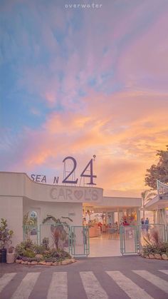 the front entrance to sea n 24 at sunset, with palm trees and bushes in the foreground