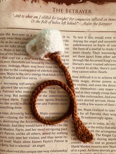 a crocheted bookmark with a white ball of yarn on top of it