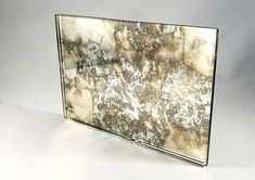 a glass frame with white and brown designs on the edges, against a gray background