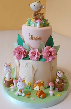 a three tiered cake decorated with animals and flowers