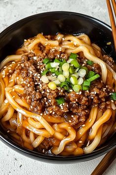 a black bowl filled with noodles and meat