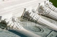 an ornate fountain with statues on it in front of a large white building and green grass