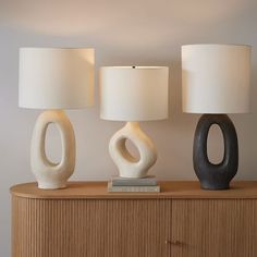 three lamps sitting on top of a wooden dresser