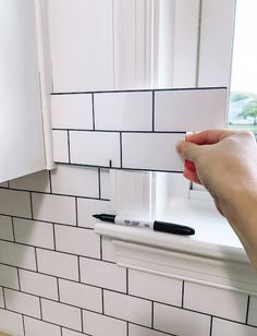 a person is holding a piece of paper in front of a window with white tiles on it