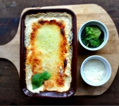 a casserole dish with spinach, cheese and sauces on the side