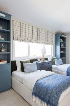 two beds in a bedroom with blue and white decor