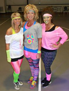 three women dressed up in costumes standing on a basketball court with their arms around each other