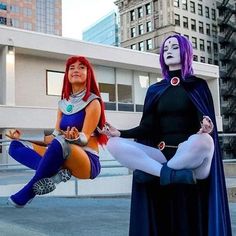 two women in costumes are sitting on the ground with their legs spread out and one woman is holding her leg up