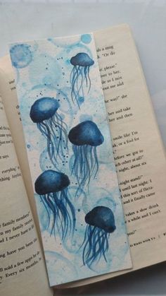 an open book with some watercolors on it and two jellyfish in the pages