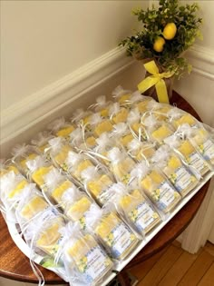 a table topped with lots of bags filled with yellow and white cakes next to a potted plant