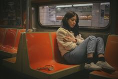 a woman sitting on a train looking at her cell phone while waiting for the subway