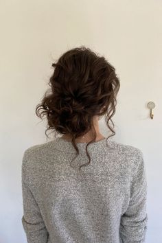 a woman standing in front of a white wall with her back turned to the camera