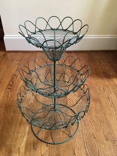 three tiered metal basket on wooden floor next to wall