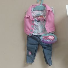 the doll is wearing a pink jacket and jeans