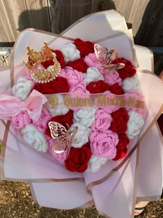 a pink and red heart shaped bouquet with roses, butterflies and a tiara on it