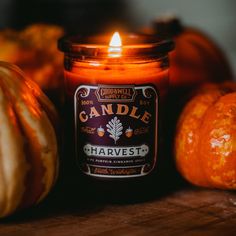 a candle sitting on top of a wooden table next to pumpkins