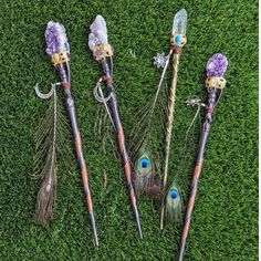 four different types of feathers on top of green grass with blue eyes and purple flowers