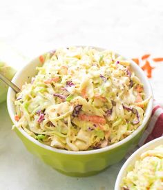 two bowls filled with coleslaw and carrots on top of a white table