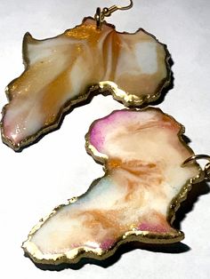 two pieces of jewelry sitting on top of a white table next to an orange and pink object