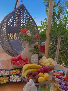 a table topped with lots of different types of fruit and pastries next to a hammock