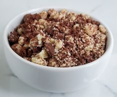 a white bowl filled with brown and white crumbs on top of a table