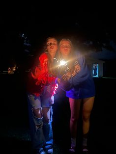 two girls are holding sparklers in the dark