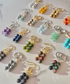 many different colored beads and gold earrings on a white table with a marble slab in the background