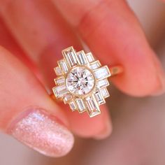 a woman's hand holding a gold ring with diamonds on it and a diamond in the middle