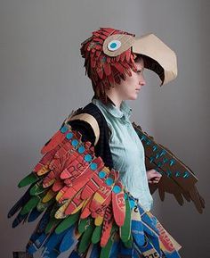 a woman in a costume made out of paper and cardboard with an owl mask on her head