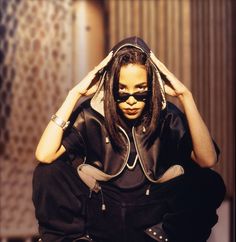 a woman sitting on the ground with her head in her hands, wearing sunglasses and a leather jacket