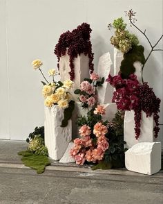 three white vases filled with flowers sitting on top of a cement floor next to each other