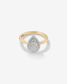 a yellow and white gold ring with a pear shaped diamond set in the center, on a plain background