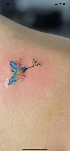 a small tattoo on the back of a woman's left shoulder that says live