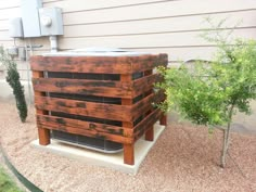 a large wooden crate sitting on top of a cement slab next to a small tree