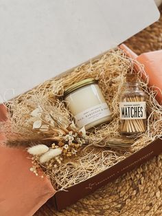 an open gift box with candles and flowers on the floor next to a straw hat