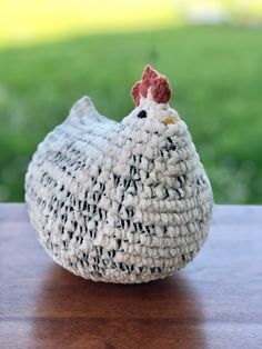 a crocheted chicken sitting on top of a wooden table