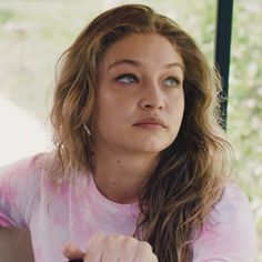 a young woman sitting at a table with her hand on her shoulder and looking off into the distance