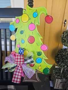 a green christmas tree with colorful ornaments on it's side and a red bow hanging from the top