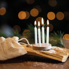 a small wooden candle holder with five white candles in front of a christmas ornament