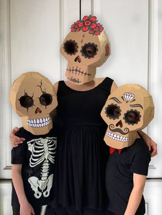 two children and an adult wearing paper skulls