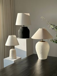 three lamps sitting on top of a table next to a vase with flowers in it