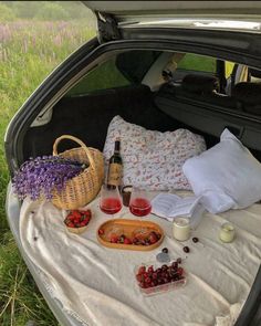 a picnic in the trunk of a car with food and drinks on it, including strawberries