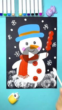 a snowman is holding a candy cane in front of some crayons