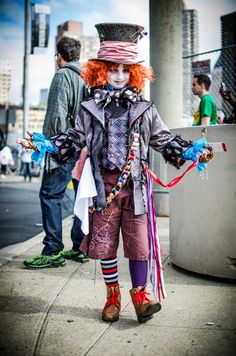 a clown dressed in costume standing on the sidewalk