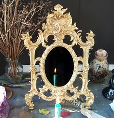 a small mirror sitting on top of a table with a lit candle in front of it